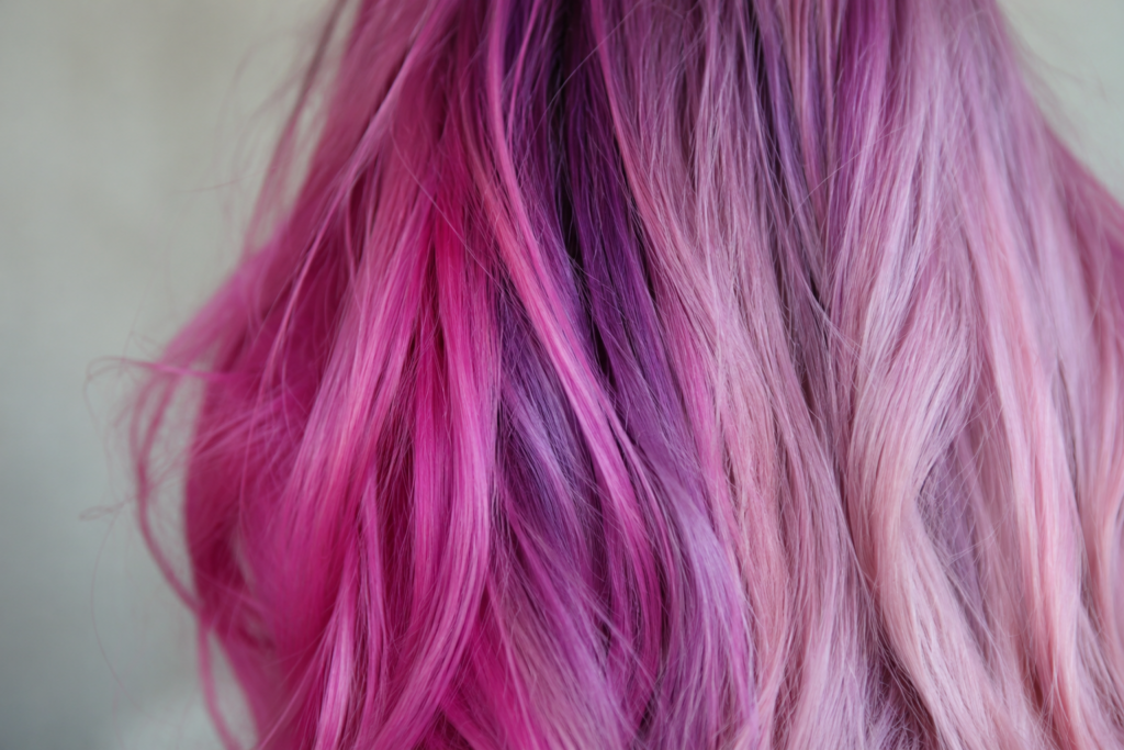 Vivid pink and purple hair strands showing color fading from root to end